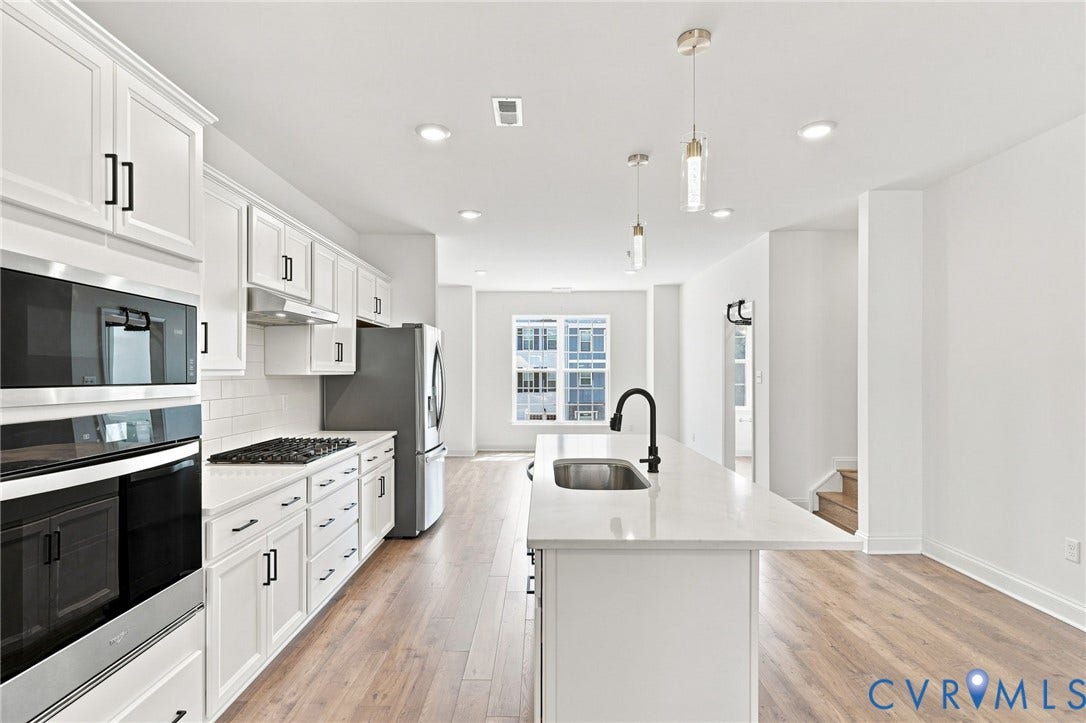 13820 Village View Drive, Midlothian, VA 23114 Bright kitchen featuring white cabinetry, integrated stainless steel appliances, a center island with sink, wood-finish flooring, and recessed lighting