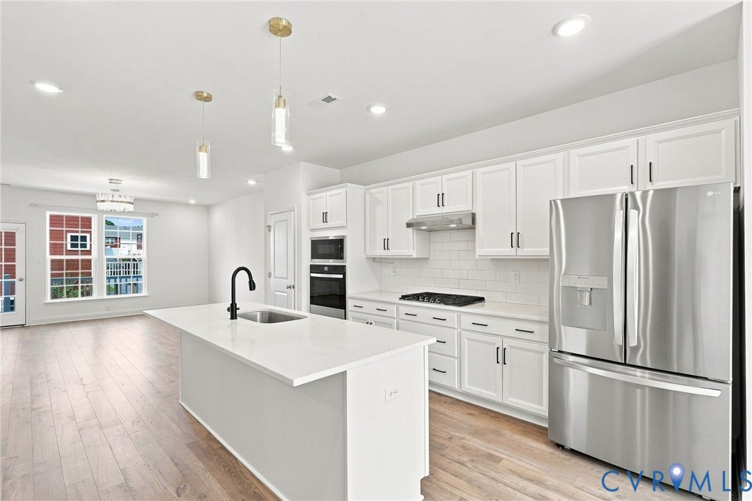 13820 Village View Drive, Midlothian, VA 23114 Open-concept kitchen featuring an island with a sink, stainless steel appliances, white cabinetry, and wood-finish flooring