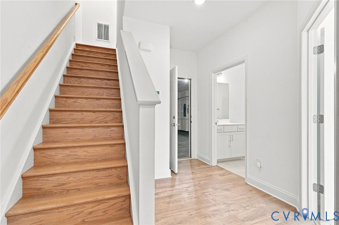 13820 Village View Drive, Midlothian, VA 23114 Wood-finish flooring, staircase with wood-finish treads and handrail, white painted walls, and white cabinetry in the adjacent room