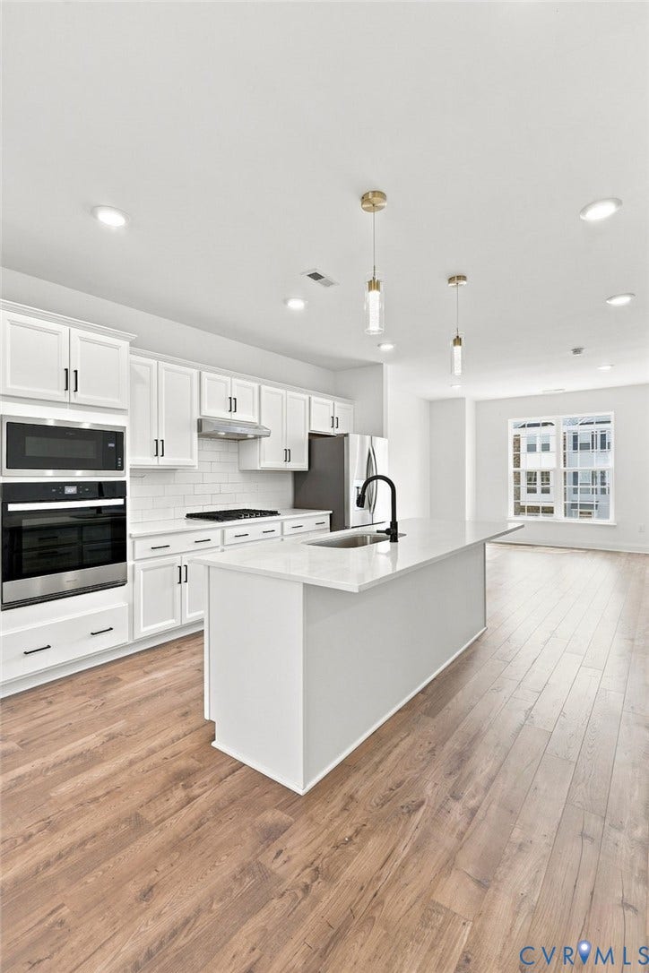 13820 Village View Drive, Midlothian, VA 23114 Modern kitchen featuring white shaker cabinetry, stainless steel appliances, a center island with sink, wood-finish flooring, and recessed lighting