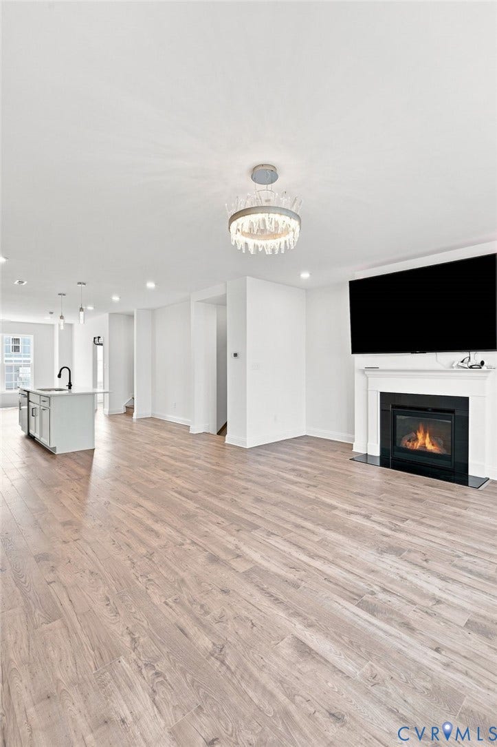 13820 Village View Drive, Midlothian, VA 23114 Spacious living area featuring wood-finish flooring, a contemporary fireplace with a white mantel, and a decorative ceiling fixture