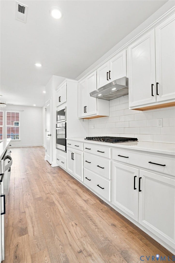 13820 Village View Drive, Midlothian, VA 23114 White shaker cabinetry with black hardware, wood-finish flooring, white subway tile backsplash, and stainless steel appliances