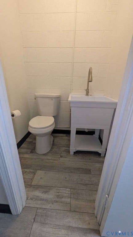 12853 Holly Lane, Manakin Sabot, VA 23103 Wood-finish flooring, white block wall, toilet, and utility sink with a brushed nickel faucet