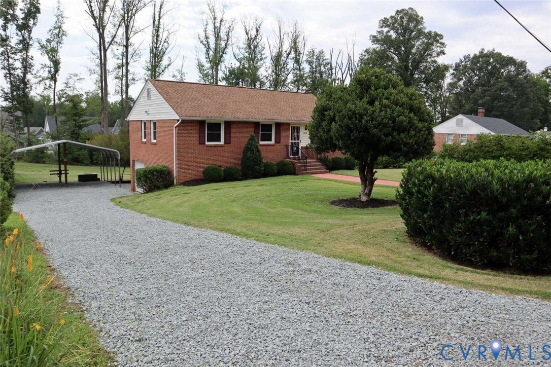 12853 Holly Lane, Manakin Sabot, VA 23103 Brick exterior residence with a gravel driveway, covered carport, manicured lawn, and mature landscaping