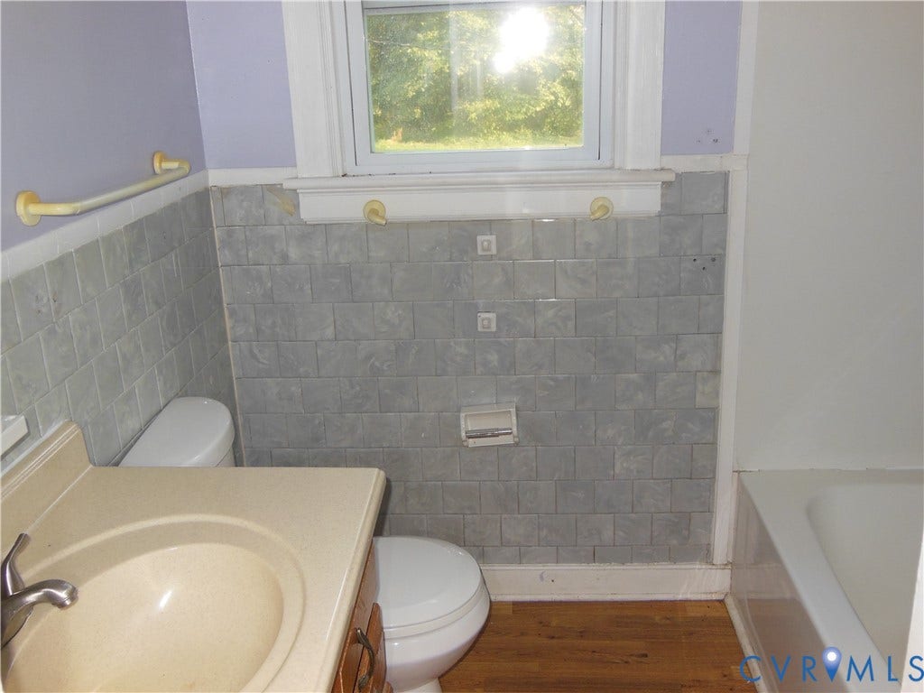 5307 Media Road, Richmond, VA 23225 Bathroom featuring a window, tile wainscoting, built-in bathtub, toilet, and vanity with an integrated sink