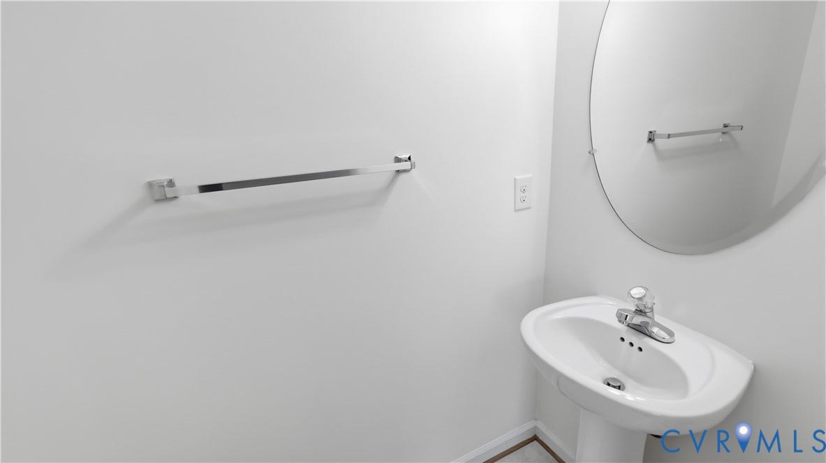 Pedestal sink with a polished chrome faucet, oval mirror, and wall-mounted towel bar