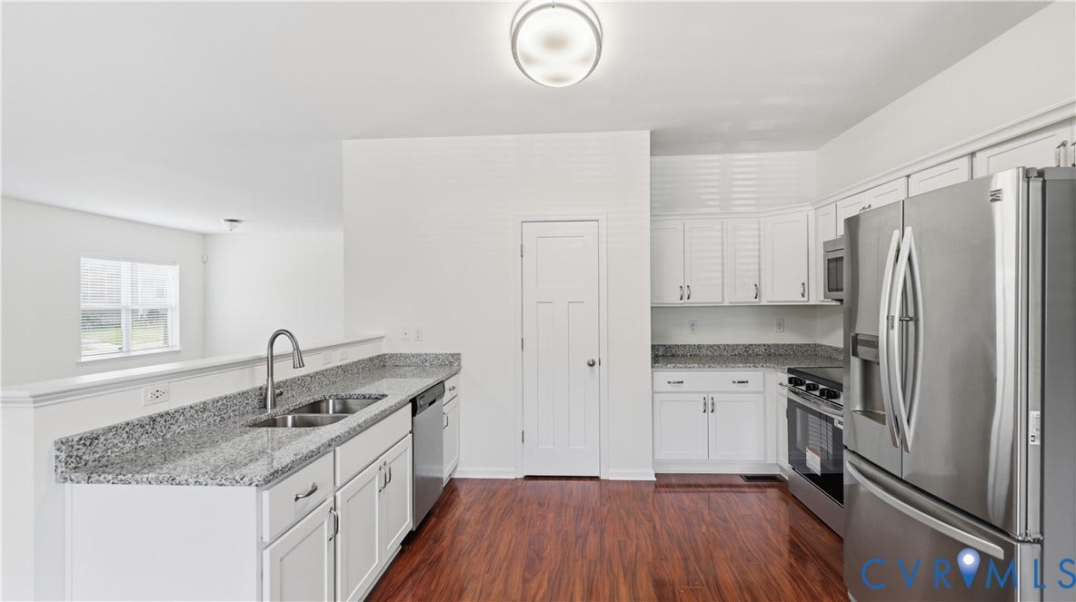 Kitchen featuring wood-finish flooring, white cabinetry, a double basin sink, stainless steel appliances, and stone countertops