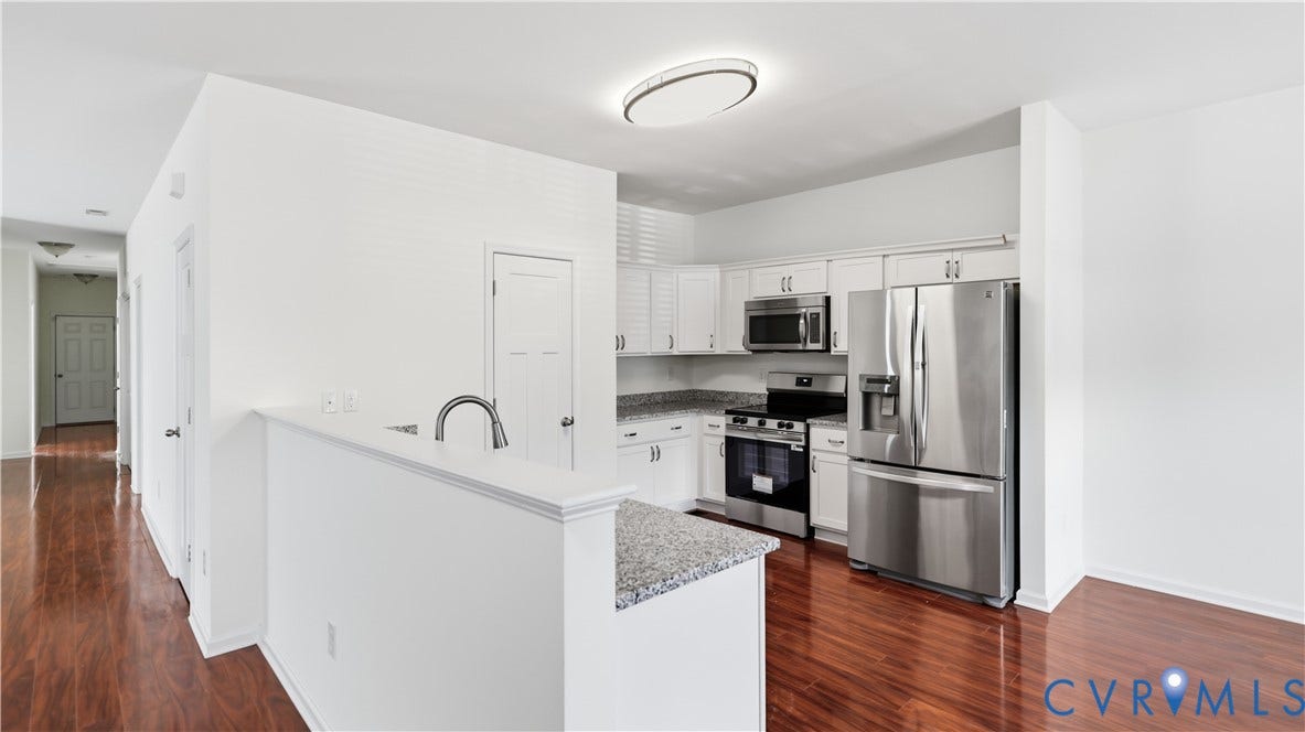 Kitchen featuring white cabinetry, stainless steel appliances, granite countertops, and wood-finish flooring