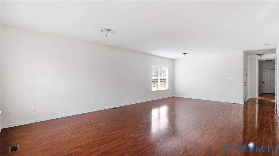 Expansive interior with wood-finish flooring, white walls, and a window