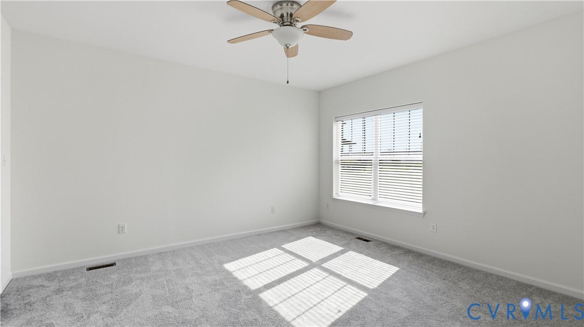 Neutral wall paint, light gray carpeting, ceiling fan with wood-finish blades, and window with blinds