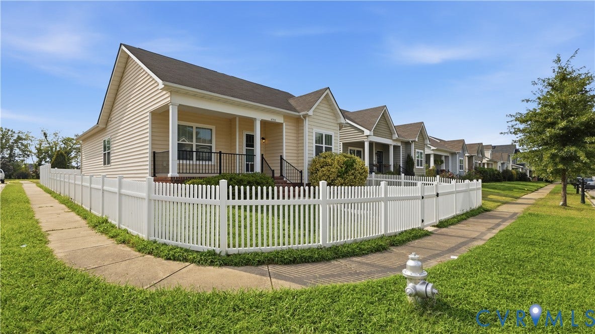 Single-story residence featuring siding exterior, covered front porch with railings, and a white picket fence