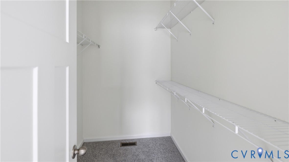 Walk-in closet featuring white wire shelving, white walls, and gray carpet