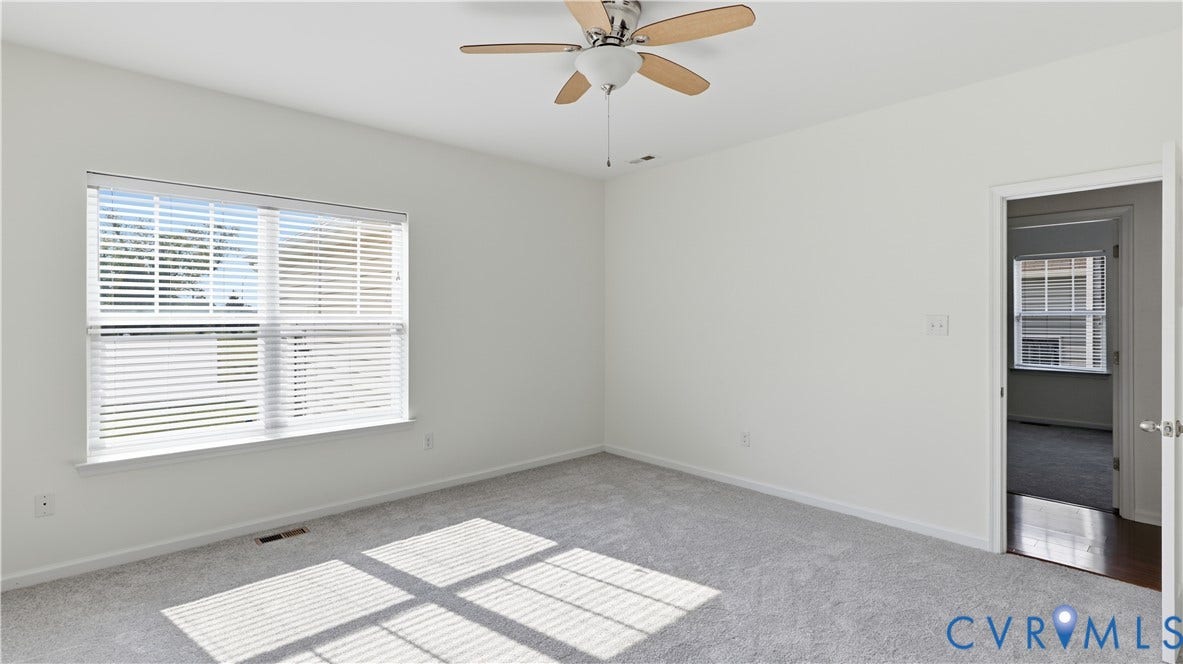Recessed window with white blinds, neutral wall finish, ceiling fan, and light gray carpeting