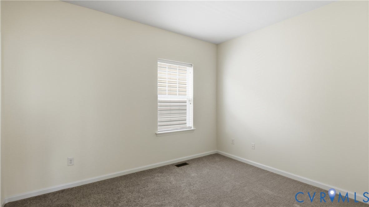 Neutral-toned walls with carpeted flooring and a single window