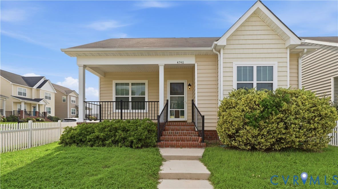 Covered front porch with white columns, brick steps, and a black wrought iron railing