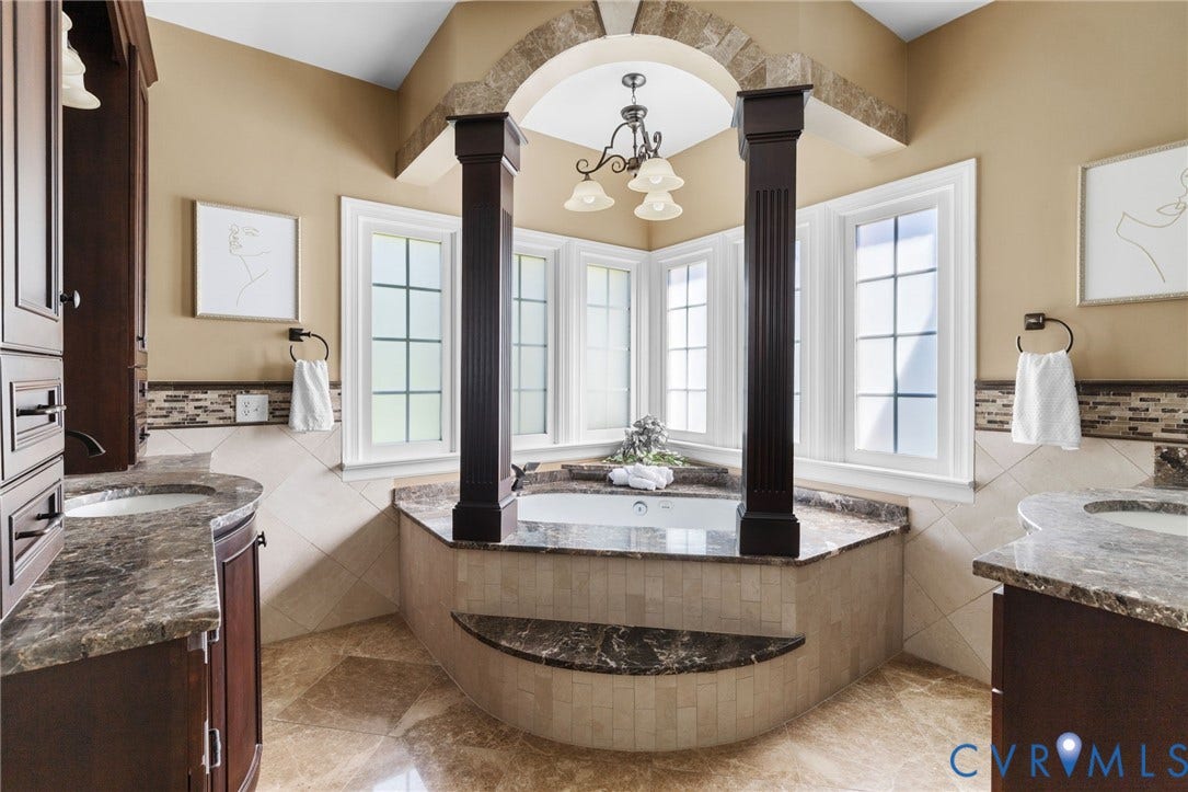 2365 Manakintown Ferry Road, Powhatan, VA 23113 Recessed corner jetted tub, dual vanities with integrated sinks, wood-finish cabinetry, stone slab countertops, and tiled flooring