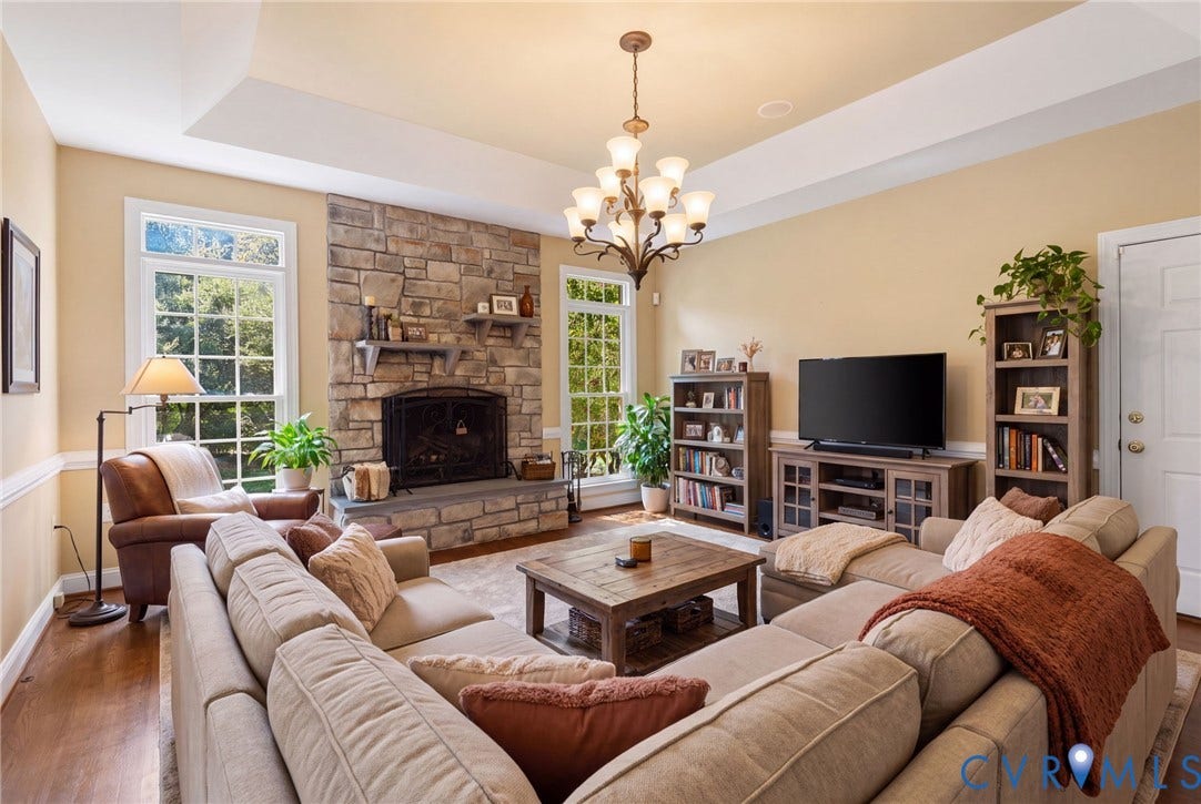 2365 Manakintown Ferry Road, Powhatan, VA 23113 Tray ceiling with a decorative chandelier, stone-surround fireplace, large windows, and wood-finish flooring