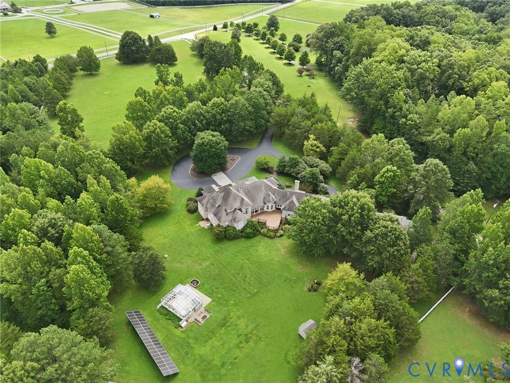 2365 Manakintown Ferry Road, Powhatan, VA 23113 Sprawling estate featuring extensive green spaces, mature tree coverage, a large residential structure with an expansive deck, a private paved driveway, and solar panel installation