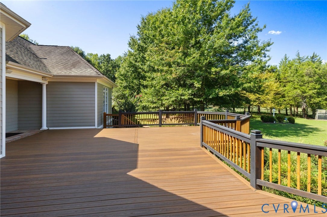 2365 Manakintown Ferry Road, Powhatan, VA 23113 Expansive wood-finish deck with dark railings and light balusters, featuring a sprawling green lawn and mature trees