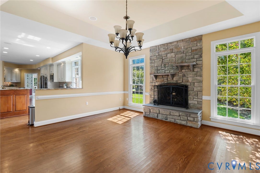 2365 Manakintown Ferry Road, Powhatan, VA 23113 Hardwood flooring, stone-clad fireplace, tray ceiling, multiple large windows, and a built-in kitchen pass-through