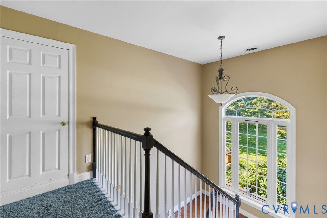 2365 Manakintown Ferry Road, Powhatan, VA 23113 Arched window overlooking exterior greenery, spindle staircase with dark wood newel posts, six-panel interior door, and pendant light fixture