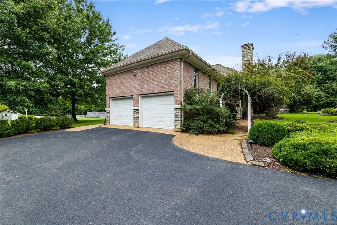 2365 Manakintown Ferry Road, Powhatan, VA 23113 Two-car garage with white doors, brick exterior with stone accents, asphalt driveway, and mature landscaping
