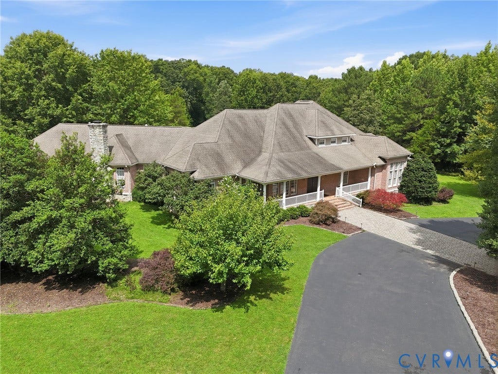 2365 Manakintown Ferry Road, Powhatan, VA 23113 Expansive property featuring a brick exterior, stone chimney, covered porch with white railing, and a multi-surface driveway with paved and stone sections