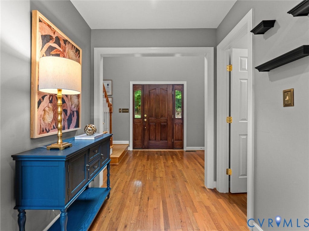 Hardwood flooring, wood entry door with glass panels, white trim, and a staircase