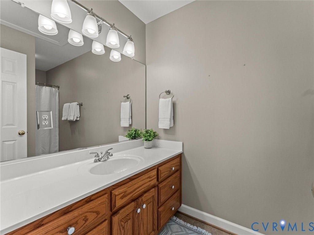 Bathroom vanity with a single basin, wood-finish cabinetry, and a white countertop