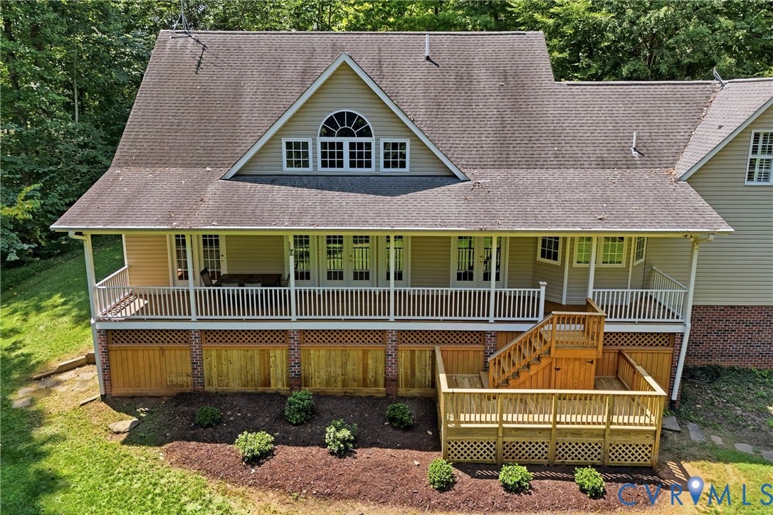 Expansive multi-level rear deck with wood railing, covered porch, and upper-level balcony with white railings