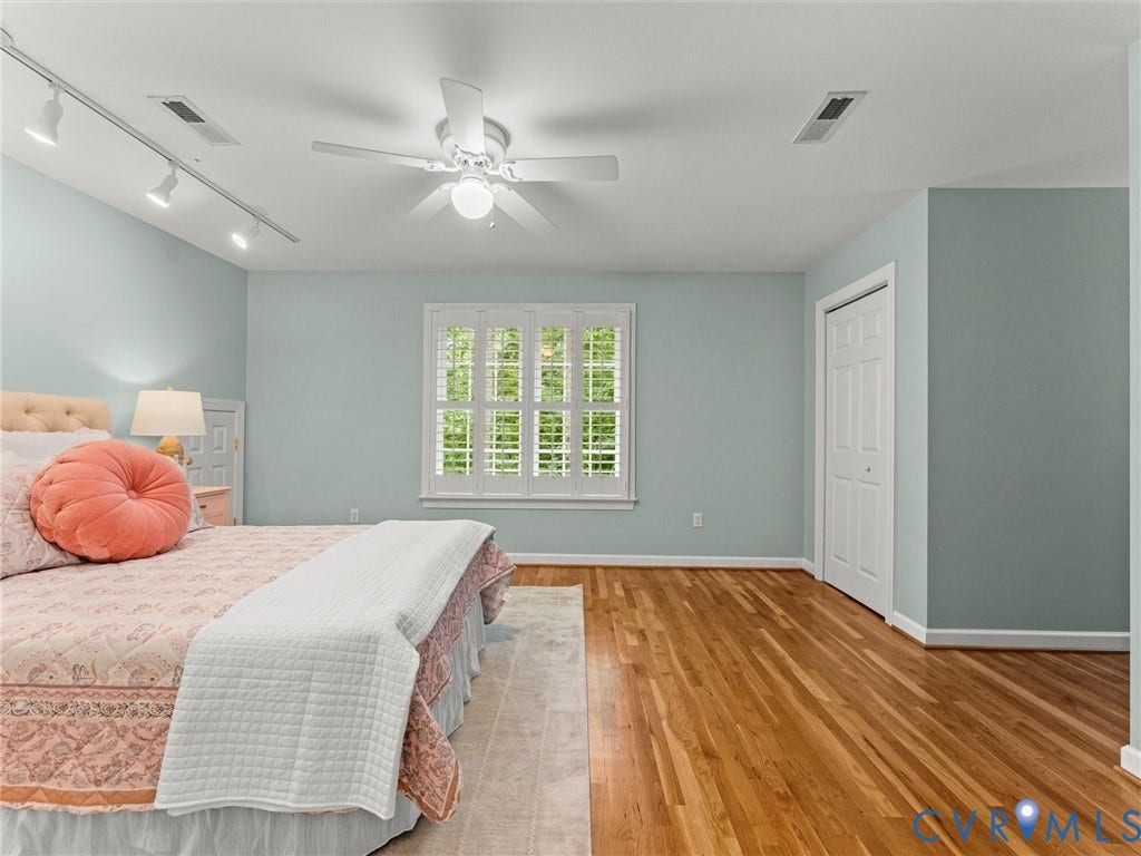 Hardwood flooring, window with plantation shutters, ceiling fan with integrated lighting, track lighting, and bi-fold closet doors