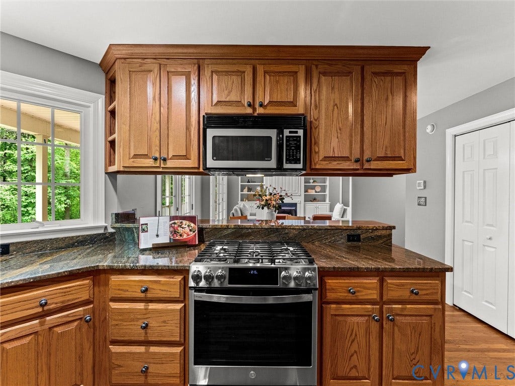 Kitchen featuring wood cabinetry, stainless steel range, built-in microwave, and stone countertops