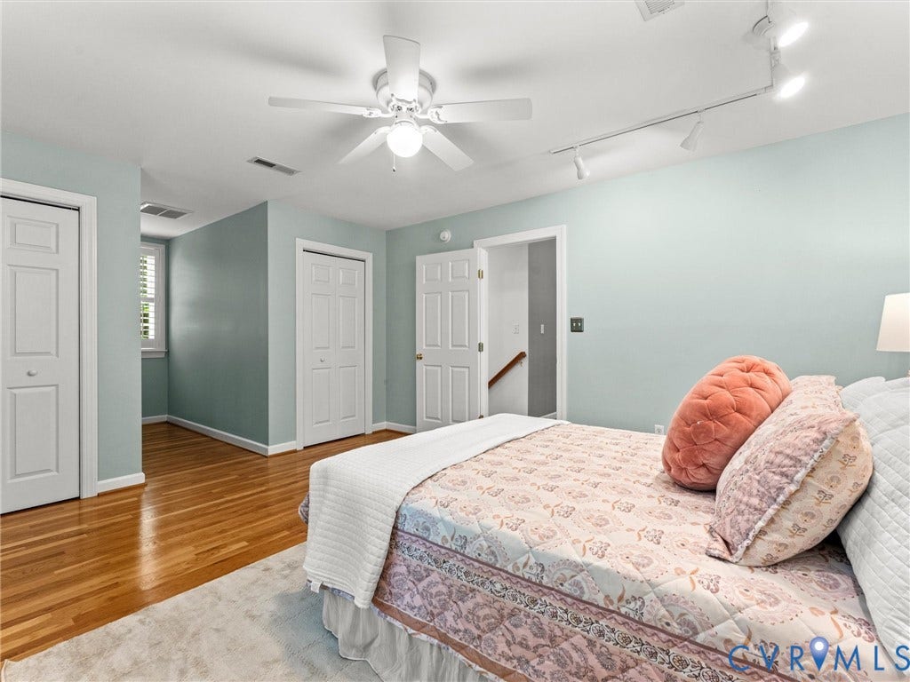 Hardwood-finish flooring, white ceiling fan, white track lighting, white bi-fold closet doors, and white window shutters