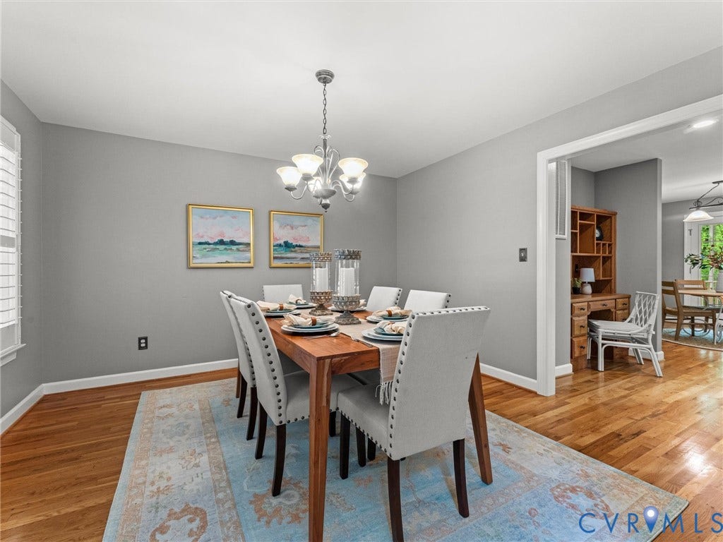 Elegant dining room featuring warm wood-finish flooring, soft gray walls, and a pendant light fixture overhead