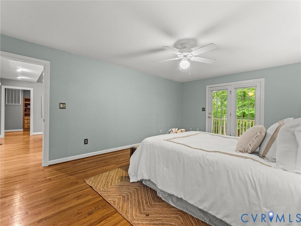 Hardwood flooring throughout, ceiling fan with integrated lighting, and white French doors opening to an outdoor area