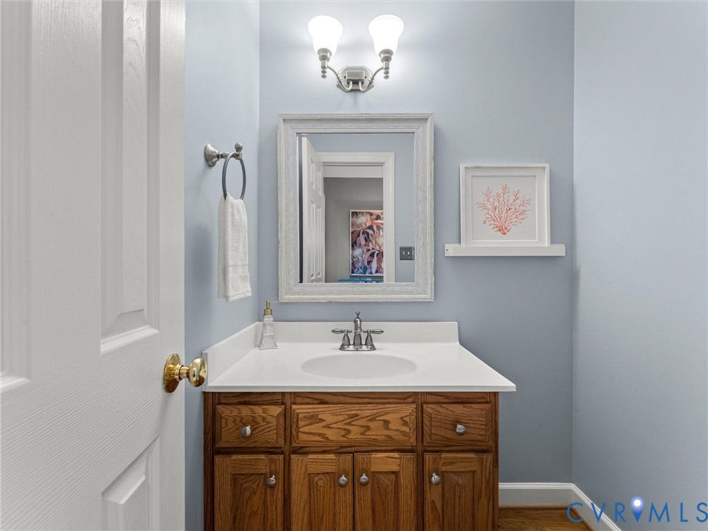 Wood-finish vanity with panel doors and drawers, white countertop, and an undermount sink