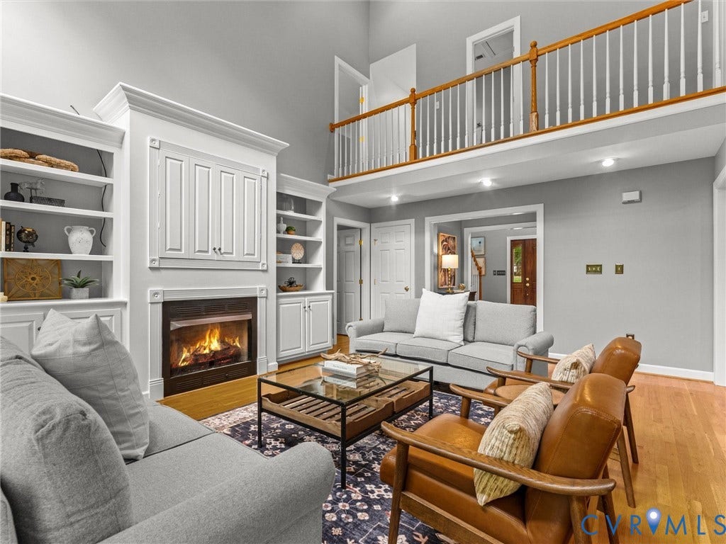 Vaulted ceiling, built-in shelving, wood-burning fireplace, interior balcony, and hardwood flooring