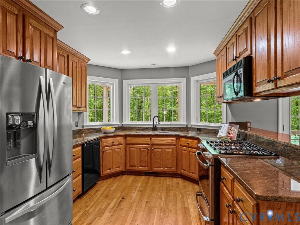 Kitchen featuring wood-finish cabinetry, stainless steel appliances, granite countertops, wood-finish flooring, and recessed lighting