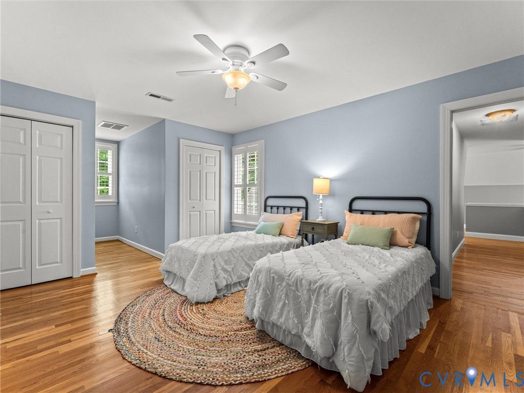 Hardwood flooring, painted walls, two windows with plantation shutters, ceiling fan, and two bifold closet doors