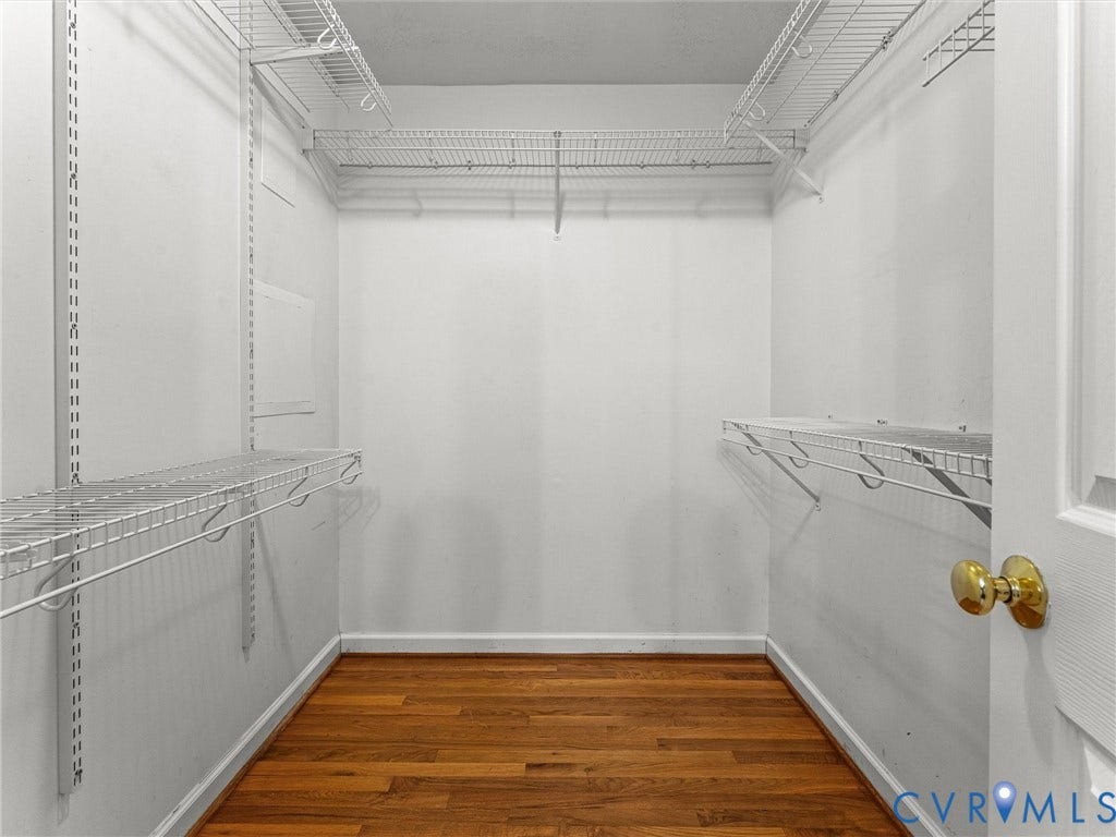 Closet featuring wire shelving system, hanging rods, wood-finish flooring, and white baseboards