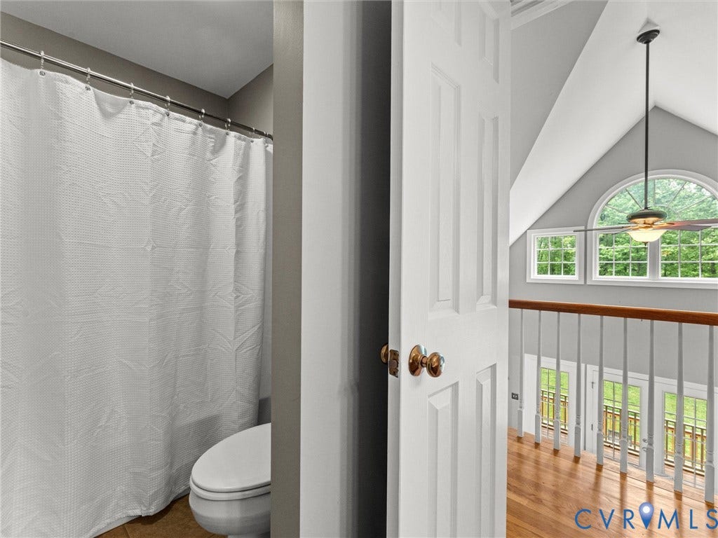 Hardwood flooring in upper-level landing with white balusters and wood handrail