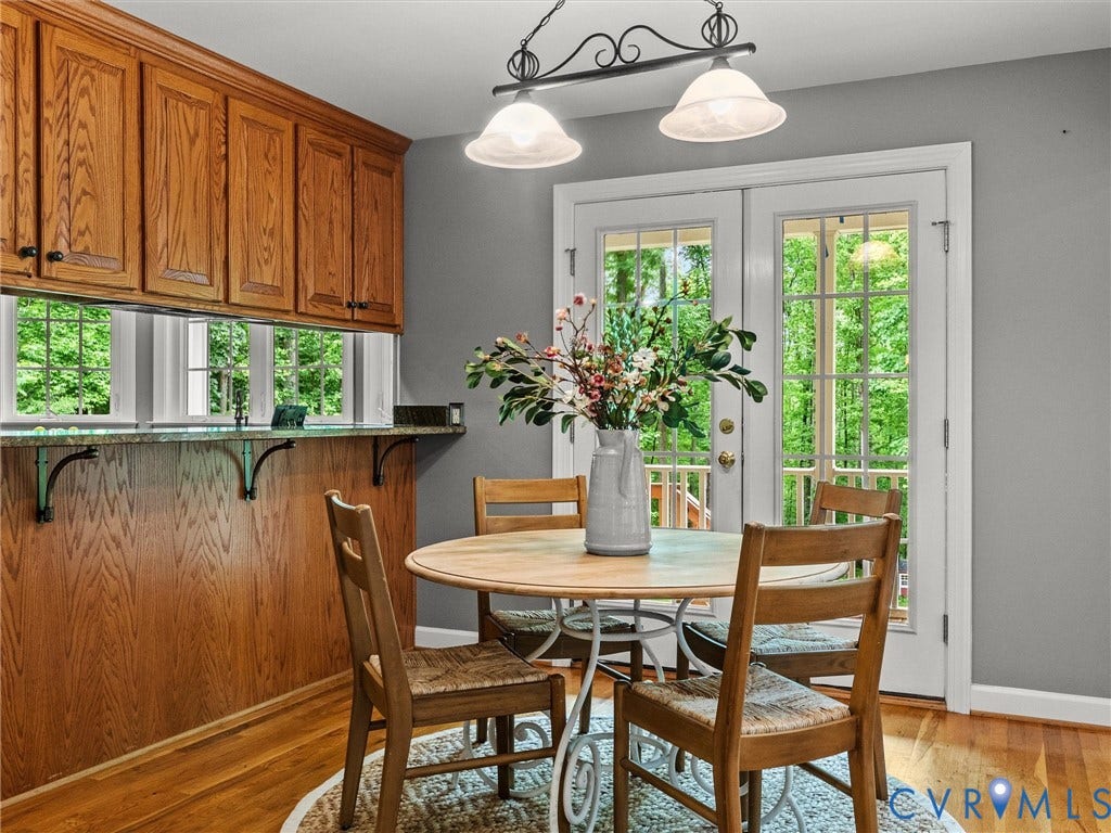 Wood cabinetry with black hardware, granite countertop, wood-finish flooring, and double patio doors