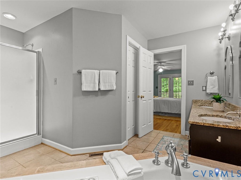 Bathroom featuring a corner shower, tiled flooring, dual sink vanity with stone countertop, and a built-in tub