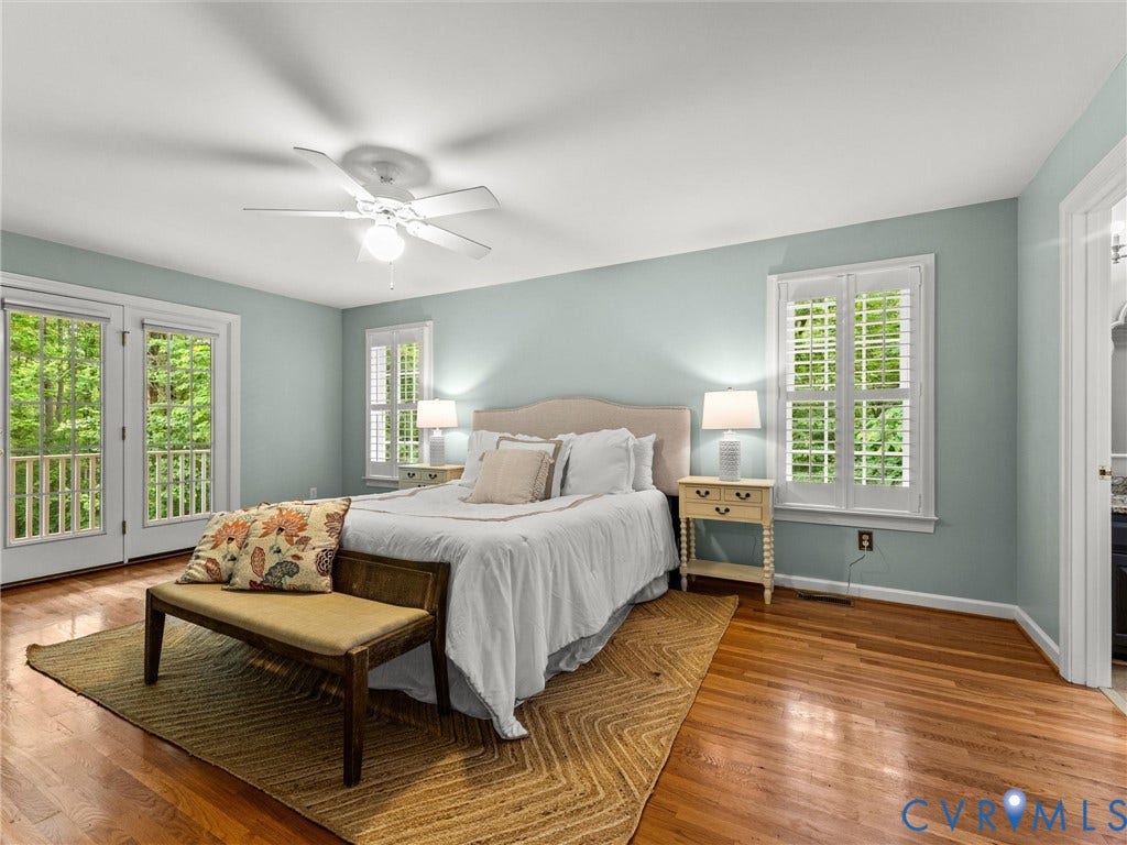 Hardwood flooring, ceiling fan, French doors with balcony access, window with plantation shutters, and a vanity with a countertop