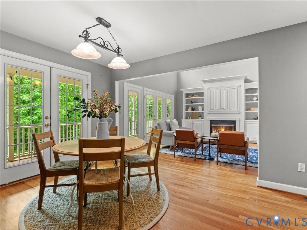 Hardwood flooring throughout, double glass-paneled doors, fireplace with built-in shelving, and a decorative ceiling light fixture