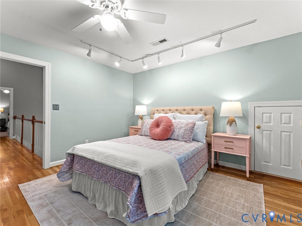 Hardwood flooring, ceiling fan, track lighting, paneled door, and wood banister