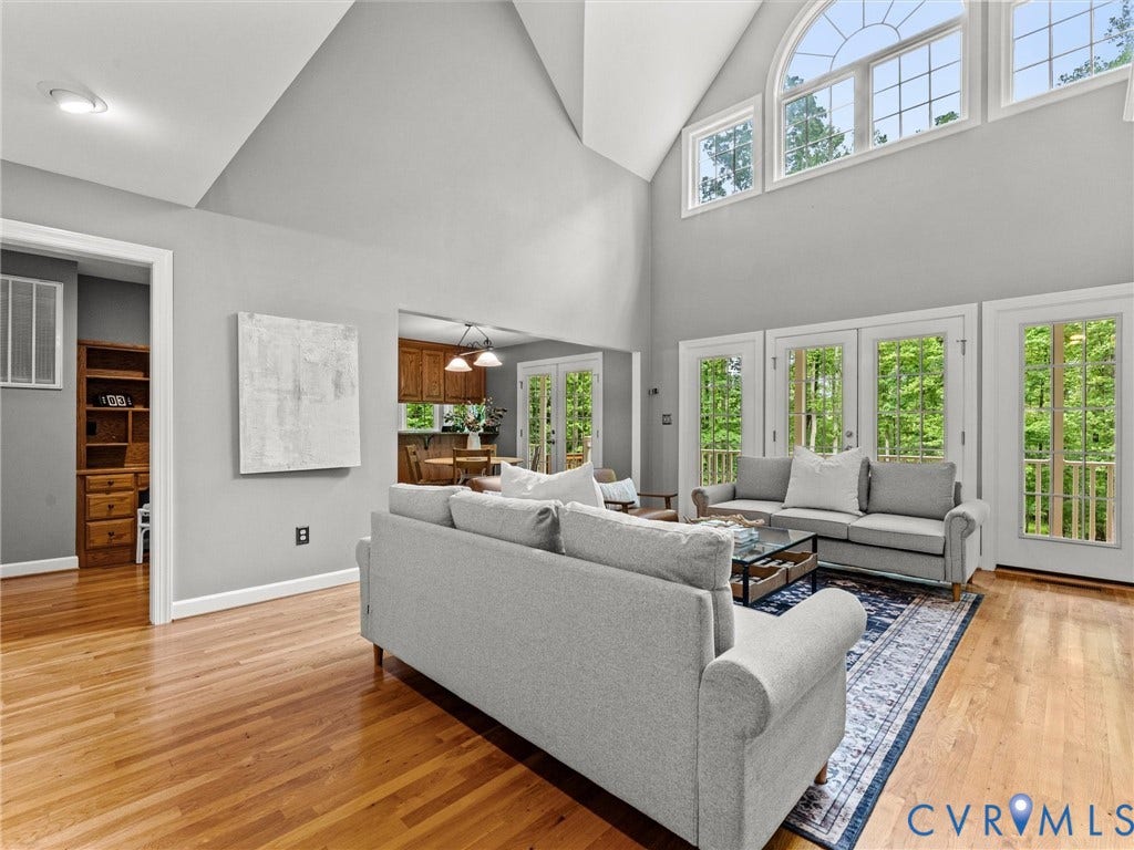 Vaulted ceilings with recessed lighting, expansive windows, multiple glass-paned doors, wood-finish flooring, and an open concept layout
