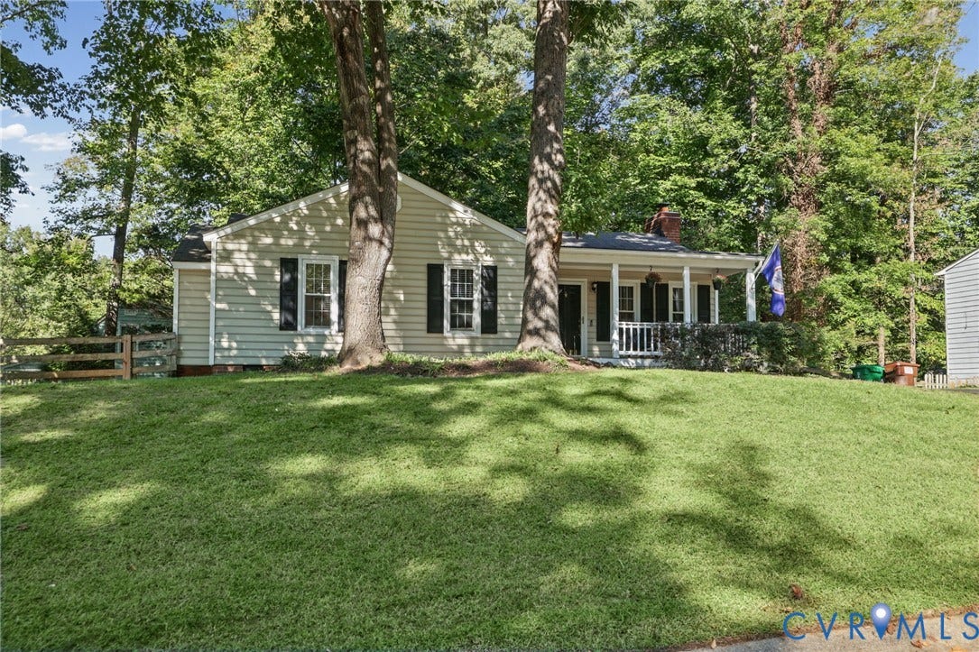13512 Master Stag Drive, Midlothian, VA 23112 Single-story residence featuring light-colored horizontal siding, a covered front porch with white railing, and dark shutters, situated on a lot with mature trees and wood-slat perimeter fencing