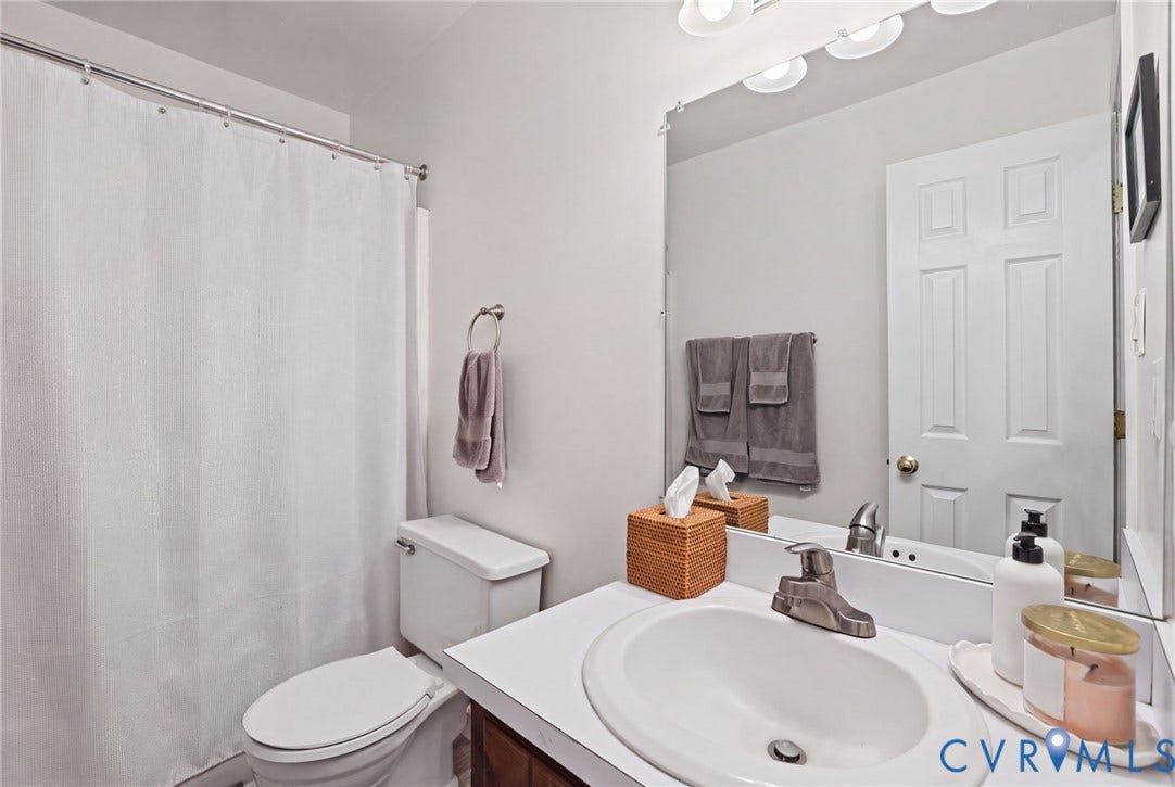 13512 Master Stag Drive, Midlothian, VA 23112 Bathroom featuring a white vanity with a molded basin, a large wall-mounted mirror, a tub-shower combination with a curtain rod, and a multi-bulb light fixture