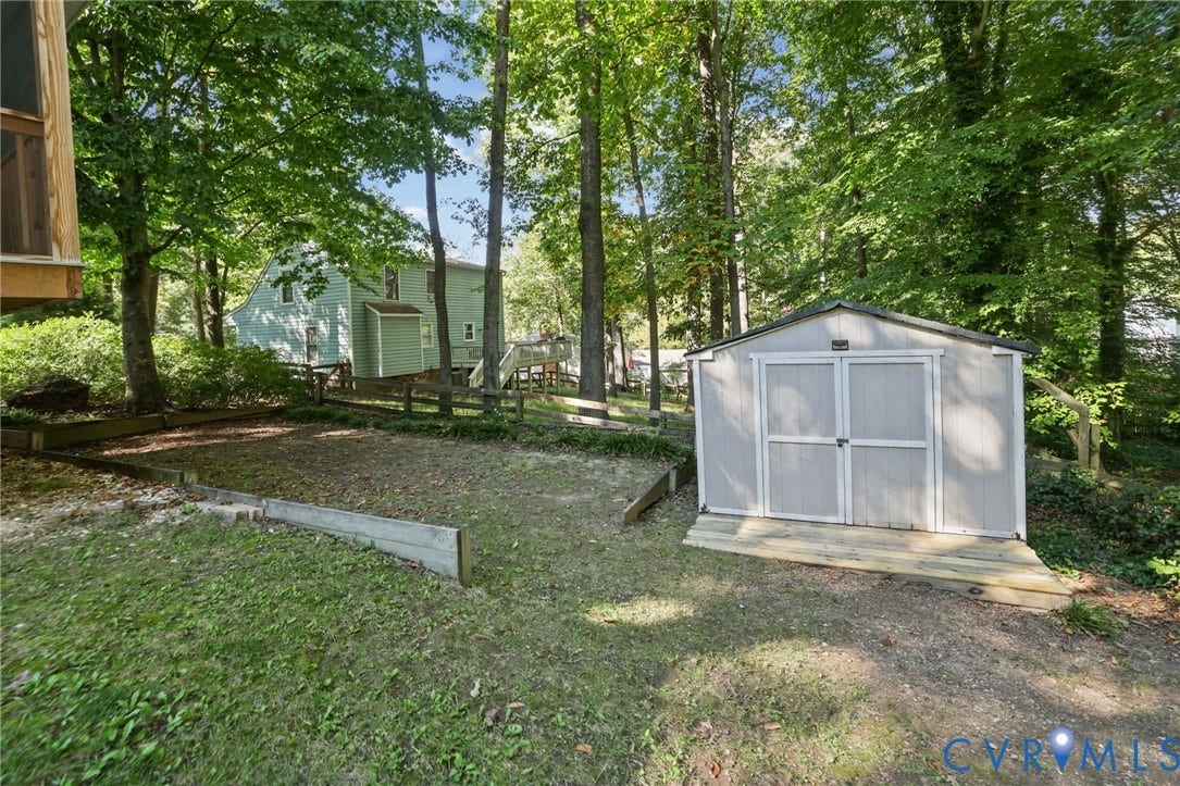 13512 Master Stag Drive, Midlothian, VA 23112 Exterior lot area featuring a detached storage shed, wood-post retaining walls, a raised deck structure, and mature trees